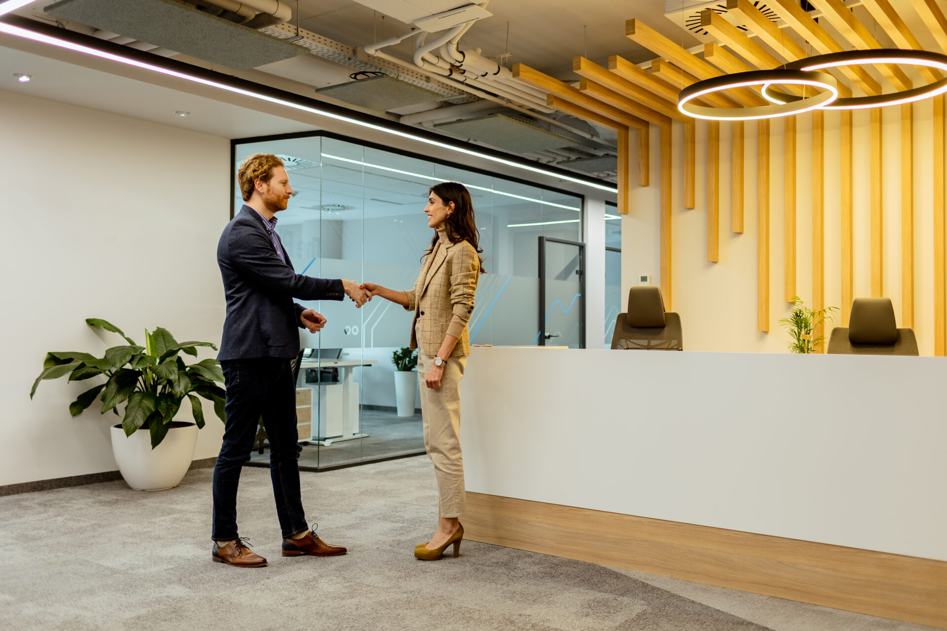 Warm Handshake Between Colleagues in Modern Commerical Office Lobby Under Ambient Lighting