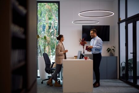 Happy business colleagues talking while working in the office under commercial lighting that was done by Kish & Sons Commercial Electrical Services.